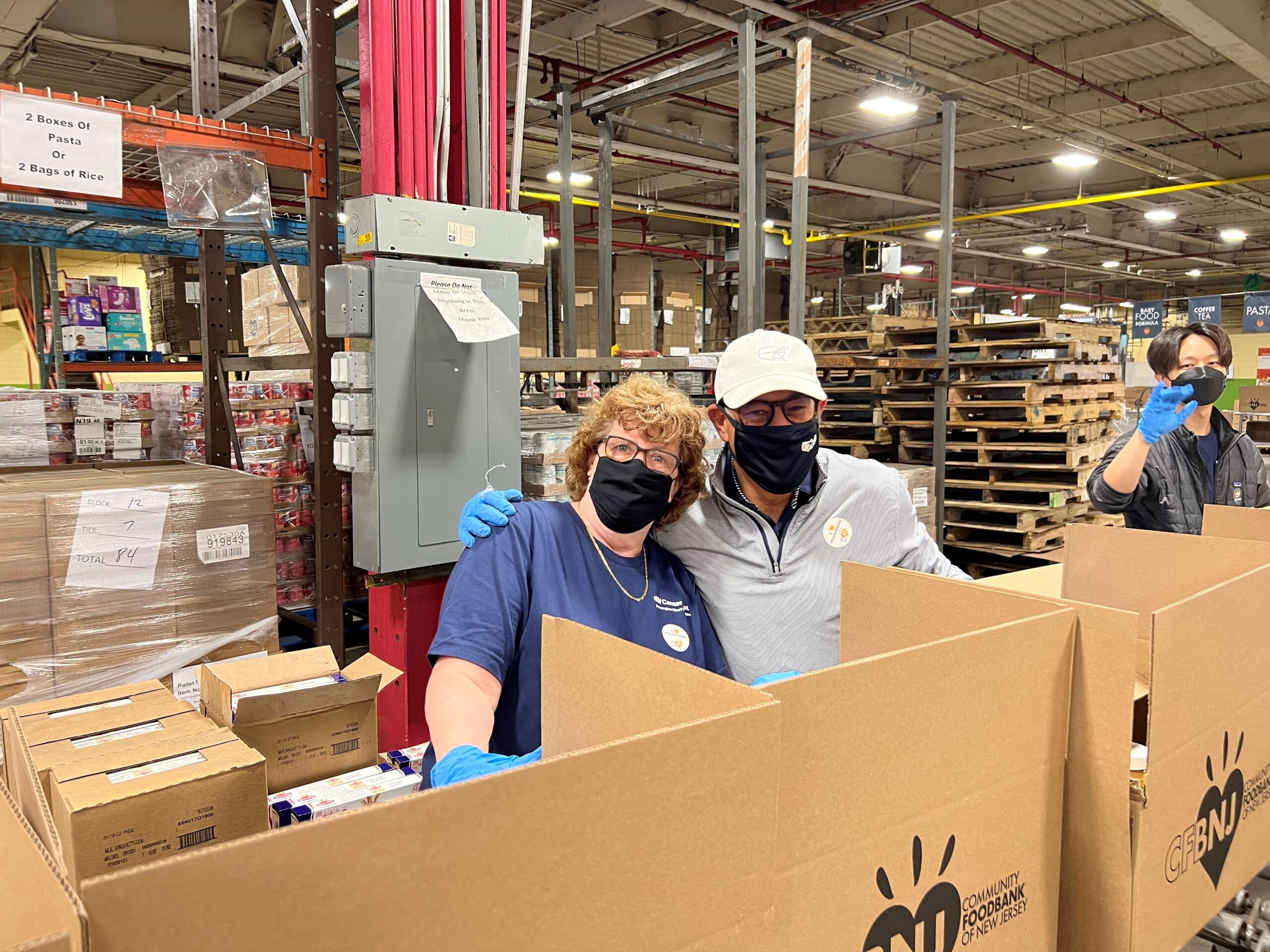 Volunteers filling boxes In warehouse with wood pallets in background